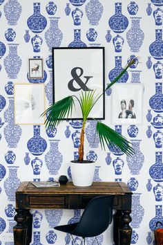 a blue and white wallpaper with a potted plant on a desk in front of it