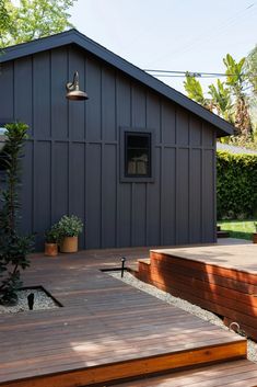 a wooden deck with steps leading up to a small gray building in the back yard