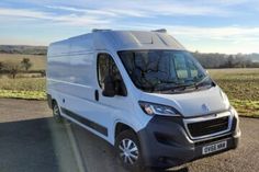 a white van is parked on the side of the road in front of an open field