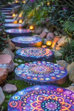 several colorful umbrellas sitting in the grass near some rocks and plants with lit candles