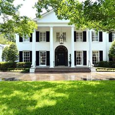 a large white house sitting on top of a lush green field