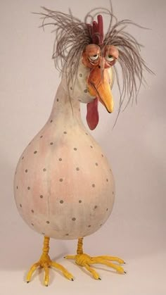 a ceramic chicken with long hair on it's head and legs, standing in front of a white background