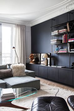 a living room filled with furniture and bookshelves in front of a large window