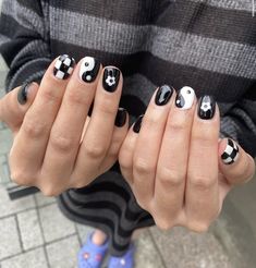 a person with black and white nail polish holding their hands together