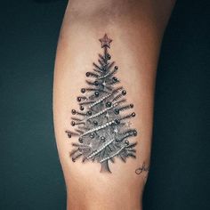 a small christmas tree tattoo on the right arm and left leg, with stars around it