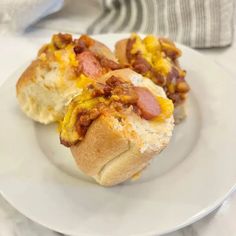 two hotdogs on a plate with cheese and bacon in the middle, ready to be eaten