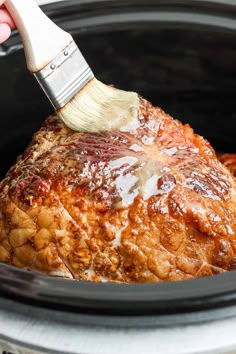 someone is using a brush to brush the meat in the slow cooker's crock pot