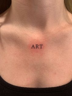 a woman's chest with the word art tattooed on her left side ribcage