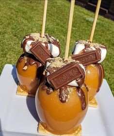 four caramel apples with chocolate and marshmallows in them on a white plate