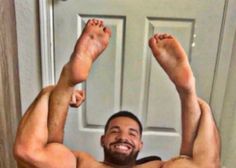 a shirtless man with his legs up in the air, posing for a selfie