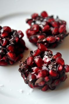 three pomegranates sitting on top of a white plate