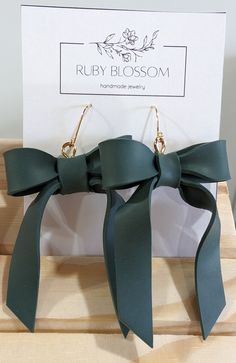 a pair of green bow earrings sitting on top of a wooden box