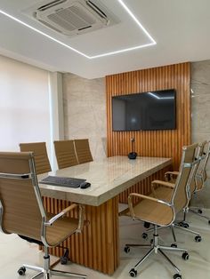 a conference table with chairs and a flat screen tv mounted on the wall above it