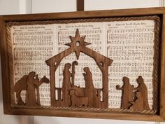 a wooden nativity scene with sheet music in the background and an old fashioned frame