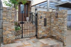 a gated entrance to a house that has stone walls and metal bars on it