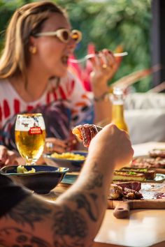 people sitting at a table eating food and drinking beer