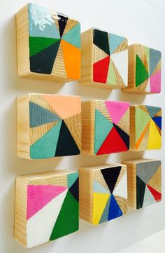 three wooden blocks are hanging on the wall with different colored shapes and colors in them