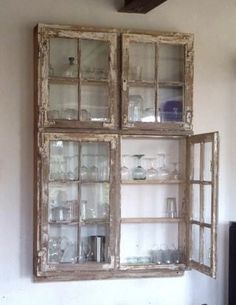 an old window is hung on the wall in front of a shelf filled with glassware