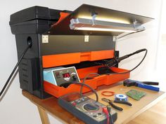 an orange and black printer sitting on top of a wooden table next to a calculator