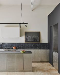 a kitchen with stainless steel cabinets and black backsplash tiles on the walls, along with an island countertop