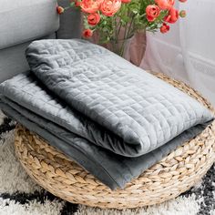 two blankets are stacked on top of each other in front of a basket with flowers