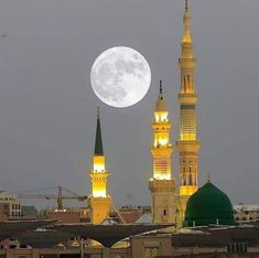 the full moon is seen behind two tall buildings