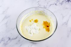 a bowl filled with cream and toppings on top of a white countertop next to a marble table