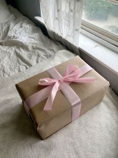 a wrapped gift box sitting on top of a bed next to a window sill