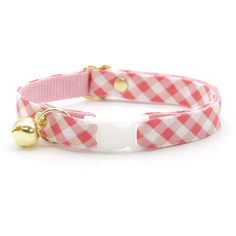 a pink and white checkered dog collar with bells on the front, and a gold bell on the back