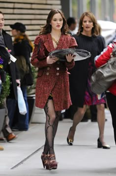 a woman is walking down the street in tights and heels with a tray on her lap