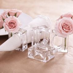 three clear vases with pink roses in them