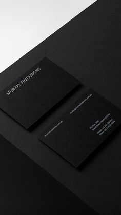 two black business cards sitting on top of a table