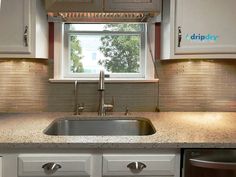 a kitchen sink under a window in front of a dishwasher and stove top