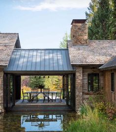 a house with a pond in front of it and stone walls around the back yard