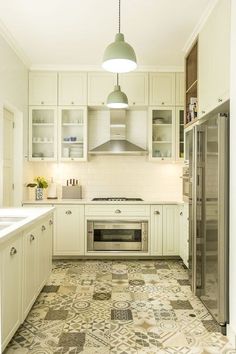 a kitchen with white cabinets and tile flooring in the center, along with stainless steel appliances