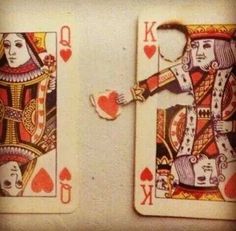 two playing cards with hearts on them sitting next to each other in front of a white wall