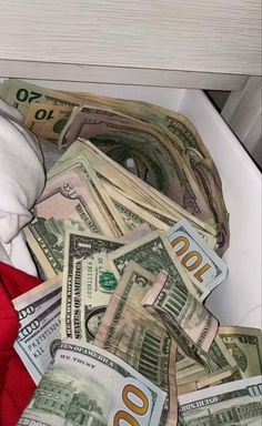 a pile of money sitting inside of a white container on top of a counter next to a red towel