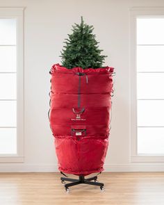 a christmas tree sitting in a red bag on top of a wooden floor