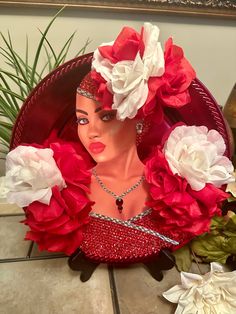 a woman with flowers in her hair wearing a red and white headdress on top of a table