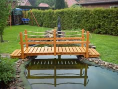 a wooden bridge over a small pond in a garden