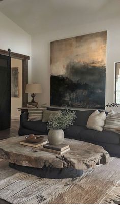 a living room filled with furniture and a large painting on the wall above it's coffee table