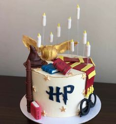 a birthday cake decorated with harry potter symbols and wands on a wooden table in front of a white wall