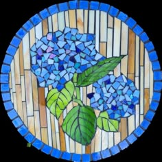 a stained glass plate with blue flowers and green leaves