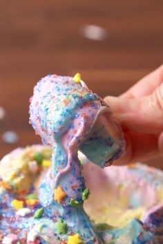 a person is holding up a doughnut with sprinkles on it and the icing has been frosted