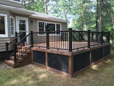 a wooden deck with black iron railings in front of a house