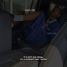 a man sitting in the driver's seat of a car with his hand on the steering wheel