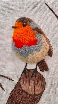 an embroidered bird sitting on top of a piece of cloth