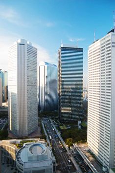 an aerial view of the city with tall buildings and cars driving on the road in front of them