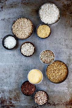 seven bowls filled with different types of rice