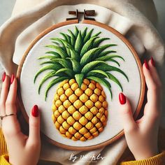 a woman's hands holding a cross stitch pineapple